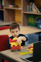 One kid choose parts of robotic electric toys for his age of four to build robots at robotics school lesson.