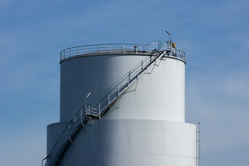 Fuel oil tanks against a blue sky with handrails and risers