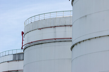 Fuel oil tanks against a blue sky with handrails and risers