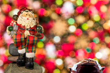 Christmas theme with Santa Claus snowman sitting and colorful background with Christmas lights.