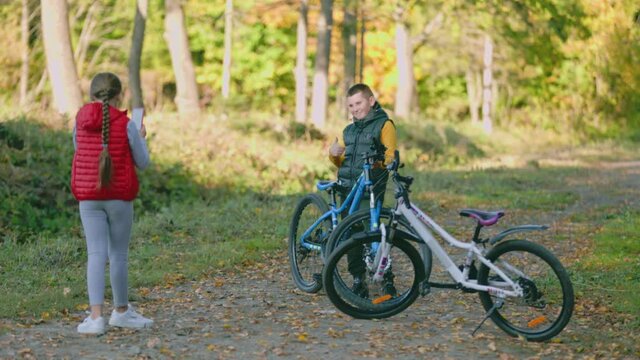 children with a bicycle are photographed on the phone in the forest