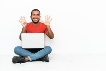 Young Ecuadorian man with a laptop sitting on the floor isolated on white background counting nine with fingers