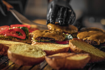 Process of cooking cheeseburgers on the grill.  Chef in black gloves cooking a hamburger