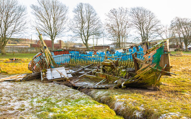 Abandoned wooden ship wreck on frost covered grass on the Dee estuary, Scotland