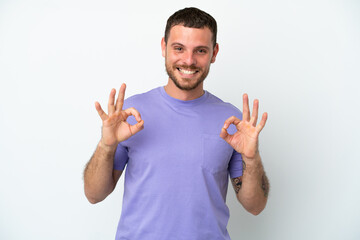 Young Brazilian man isolated on white background showing ok sign with two hands