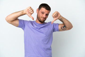 Young Brazilian man isolated on white background showing thumb down with two hands