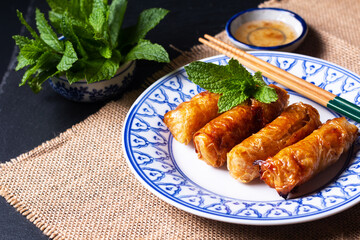 Food concept Vietnamese fried Rice paper spring rolls with mints on black background with copy space