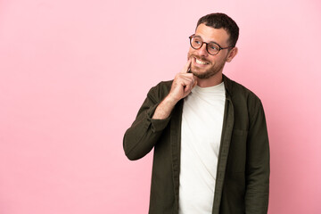 Young Brazilian man isolated on pink background thinking an idea while looking up