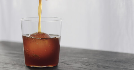 coffee pour over ice ball in tumbler glass on black wood table