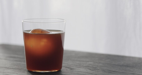 coffee pour over ice ball in tumbler glass on black wood table