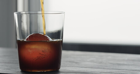 coffee pour over ice ball in tumbler glass on black wood table