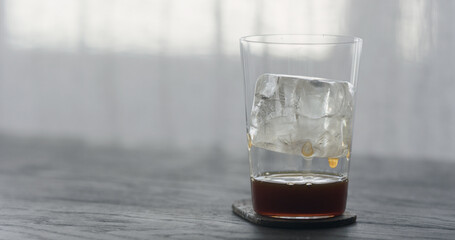 coffee pour over ice cube in tumbler glass on black wood table