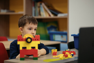 One kid choose parts of robotic electric toys for his age of four to build robots at robotics school lesson.