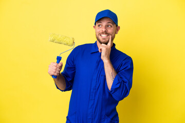 Painter Brazilian man isolated on yellow background thinking an idea while looking up
