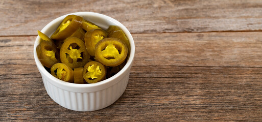 pickled sliced green jalapeno peppers in white bowl. Copy space
