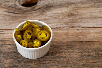 pickled sliced green jalapeno peppers in white bowl. Copy space