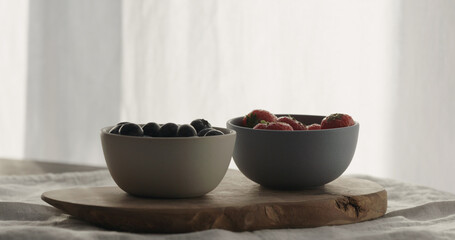strawberries and blueberries in bowls on wood table