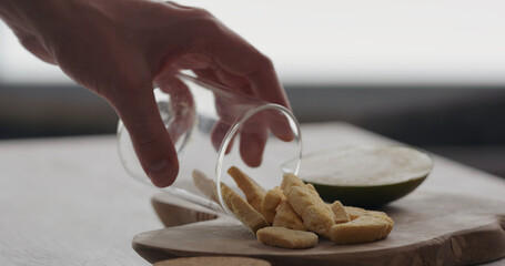 man pour freeze dried mango from glass jar on olive wood board