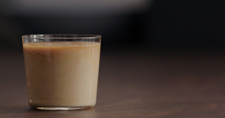 pour milk into ice coffee on black walnut table