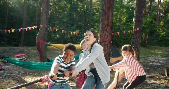 Cropped view of the kids at summer camp playing tug or war with each other at the forest. Happy childhood and activities concept