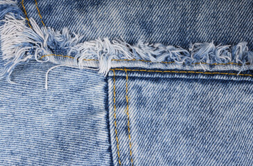 Old blue jeans with ragged edges and texture. Denim seam. 