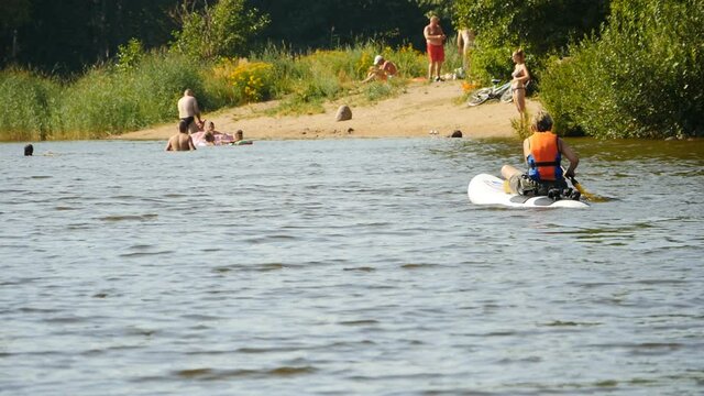 river summer child controls windsurfing with rowing paddles sitting astride