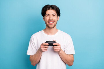 Photo of funny young brunet guy playstion wear white t-shirt isolated on blue color background