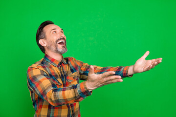 Portrait of attractive cheerful man catching copy empty space isolated over bright green color background