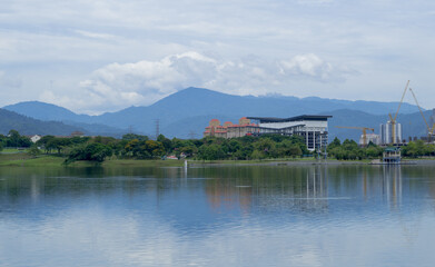 Naklejka premium Landscape of Kepong lake in Kuala Lumpur during sunny day with reflection on water, clouds and mountains in the background. 