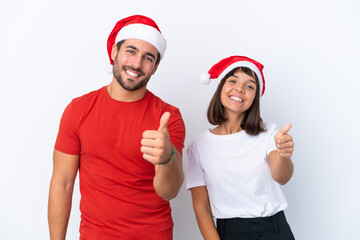 Young couple with christmas hat isolated on white background giving a thumbs up gesture because something good has happened