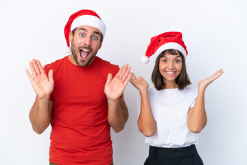 Young couple with christmas hat isolated on white background with surprise and shocked facial expression