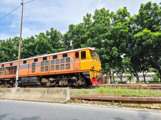 fast orange train on rail in bangkok. heavy diesel engine transportation industrial cargo vehicle.