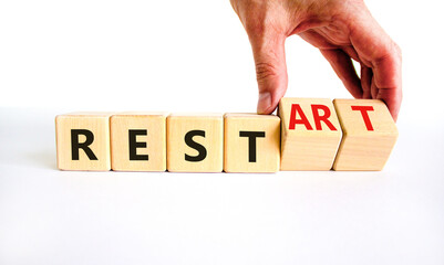 Rest and restart symbol. Businessman turns wooden cubes and changes the word 'rest' to 'restart'. Beautiful white background, copy space. Business, rest and restart concept.