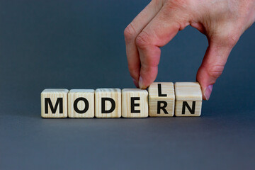 Modern model symbol. Businessman turns wooden cubes and changes the word 'model' to 'modern'. Beautiful grey table, grey background, copy space. Business and modern model concept.