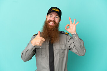 Redhead security man isolated on white background showing ok sign and thumb up gesture