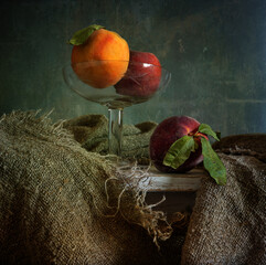 Ripe peaches in a glass vase and another on the table.