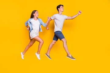 Fototapeta na wymiar Full length body size view of handsome beautiful couple jumping running good mood isolated over vivid yellow color background