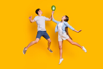Fototapeta na wymiar Full length body size view of handsome beautiful trendy couple jumping celebratory isolated over vivid yellow color background