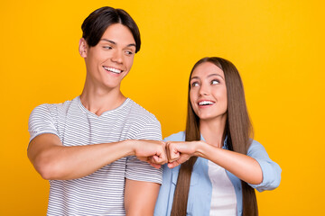 Portrait of attractive cheerful couple partners touching fists support isolated over bright yellow...