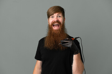 Tattoo artist redhead man isolated on blue background with surprise facial expression