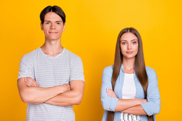 Portrait of attractive content cheery couple partners coworkers folded arms isolated over bright yellow color background