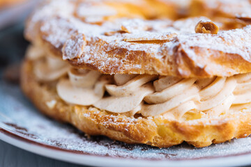 Dessert called Paris Brest on a grey background with powder sugar and almond leaves and almond creme between - obrazy, fototapety, plakaty