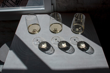 Composition of glasses filled with white wine and shadows