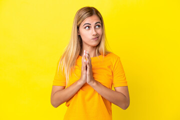 Blonde Uruguayan girl isolated on yellow background scheming something