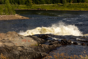 Rockcarvings located at Nämforsen, with waterfall in the background.