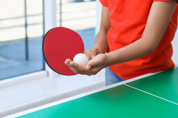 Little girl playing ping pong indoors, closeup