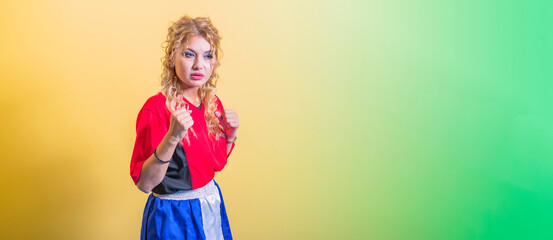 Young girl fighter in tracksuit stands in protective stance of boxer with her hands high. Palms are clenched into fists. Distant look.
