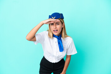 Airplane stewardess Uruguayan woman isolated on blue background looking far away with hand to look something