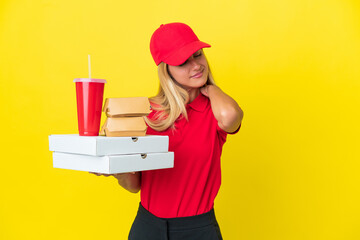 Delivery Uruguayan woman holding fast food isolated on yellow background suffering from pain in shoulder for having made an effort