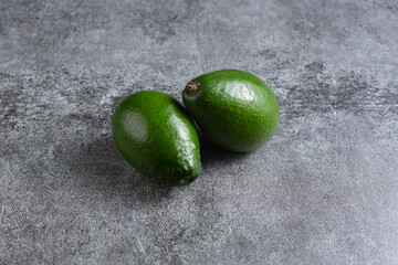 two green avocados lie on an artificial stone board. diet food. green vegetable.
